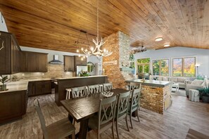 A spacious kitchen with a wooden ceiling, a central island, and a dining area with a bench. - Summit View Ski and Golf Retreat w/hot tub & Sauna (Winhall)