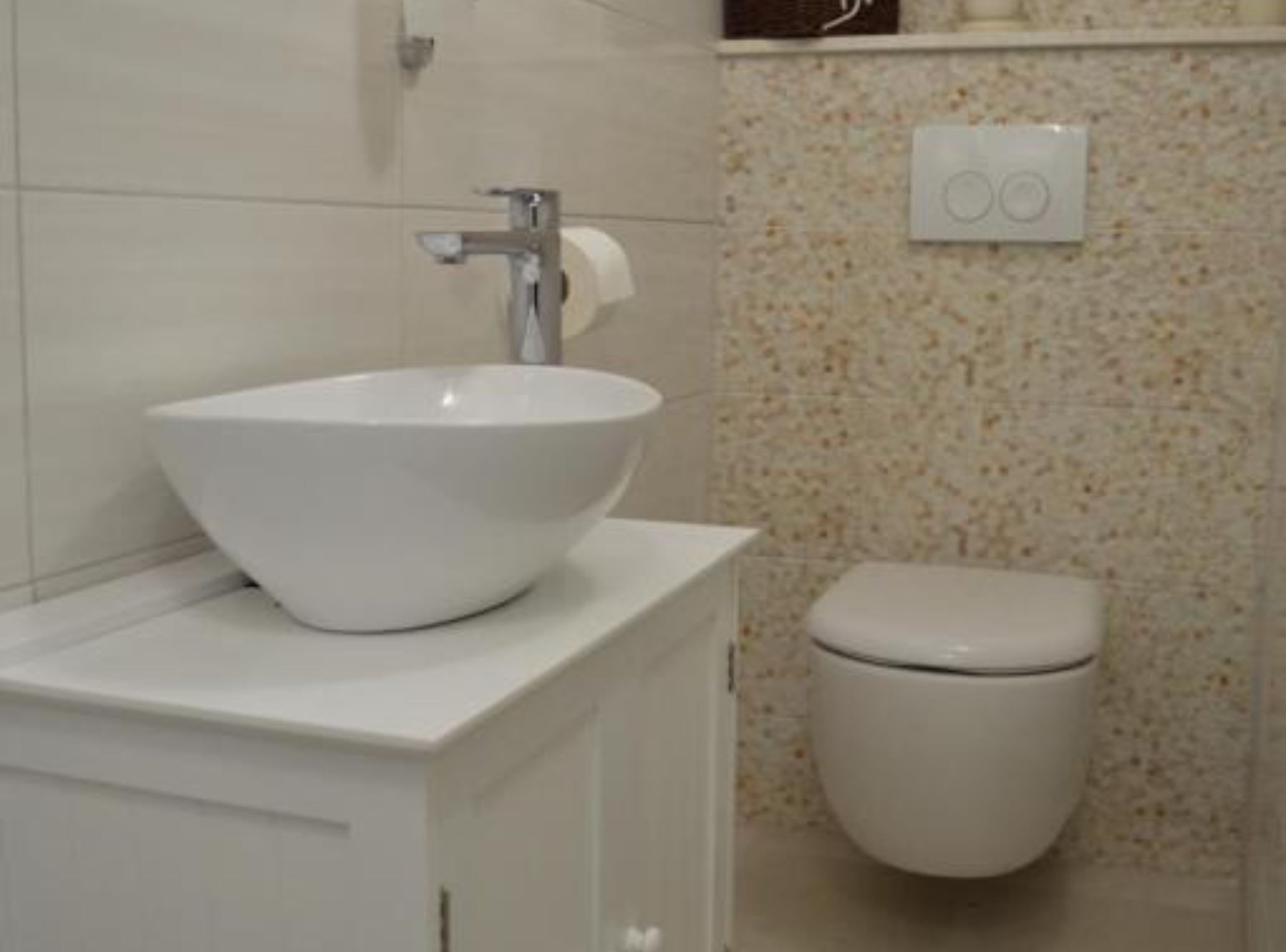 A bathroom with a white sink, a toilet, and a wall-mounted light switch.