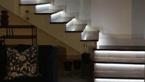 A modern staircase with built-in lighting, a sofa with a floral pattern, and a small table. - Villa Seka (Rogoznica)