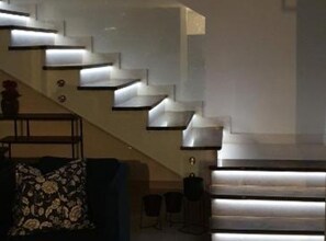 Eine moderne Treppe mit integrierter Beleuchtung, ein Sofa mit floralem Muster und ein kleiner Tisch.