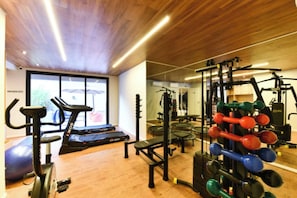 Ein Fitnessstudio mit Cardiogeräten, Gewichtstrainern und einer Spiegelwand.