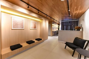 Ein modernes Interieur mit Holzboden, einer Rezeption mit schwarzen Kissen und gerahmten Kunstwerken an der Wand.