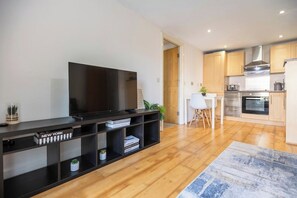Un soggiorno moderno con una TV a schermo piatto, un mobile TV nero e un'area pranzo con un tavolo e sedie bianche.