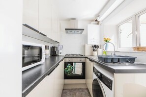 A compact kitchen with a microwave, stove, oven, and washing machine.
