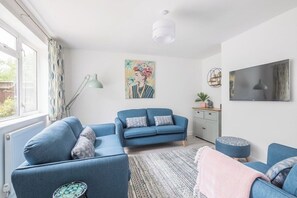 A living room with a blue sofa, a patterned rug, and a painting on the wall.