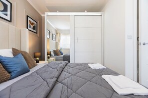 A hotel room with a bed, bedside tables, a wardrobe, and framed artwork on the wall.