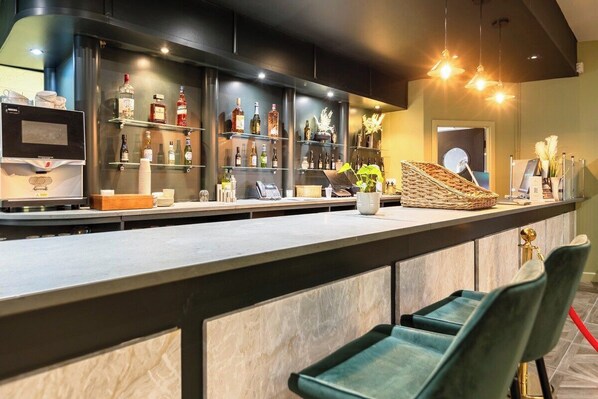 Un espace bar avec des étagères remplies de bouteilles, une caisse enregistreuse et des tabourets de bar.