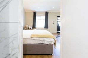 Une chambre à coucher avec un lit, un canapé, une fenêtre avec des rideaux et une porte.