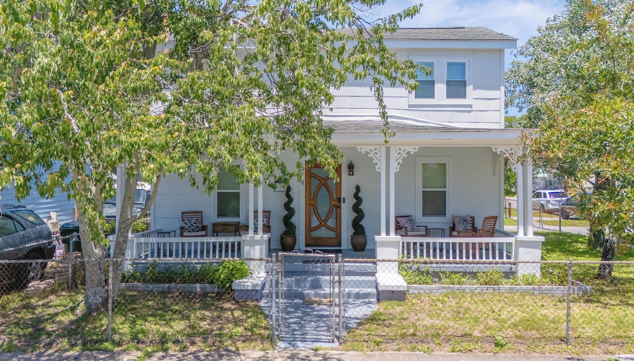 A two-story house with a porch, a wooden door, and a small front yard.