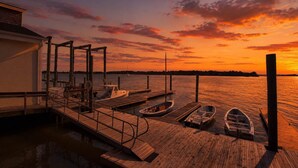 A wooden dock with boats, a building, and a sunset over water. - Walk to Downtown Beaufort | 4BR Coastal Cottage (Beaufort)