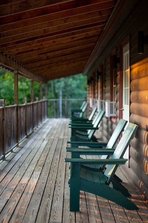 A covered porch with wooden flooring and green chairs.. Two room Riverfront Suite in West Forks