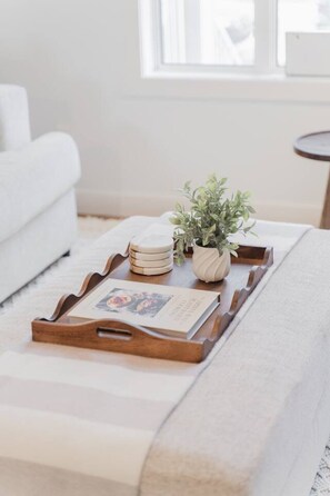 A wooden tray with a book and a small plant on a white ottoman. - Stylish Escape|9 Min to WEM|AC|Gym|Sauna & Patio (Edmonton)