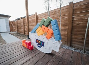A Tetris game setup on a wooden deck with a wooden fence in the background. - Chic Central 3BR: Martini Bar & Patio. Near DT/WEM (Edmonton)