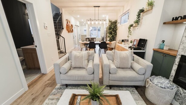 Un salon moderne avec un ensemble de canapés, une table basse agrémentée d’une plante, et un coin repas à l’arrière-plan.