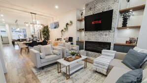 Un salon moderne avec une cheminée, un téléviseur fixé au mur et un coin repas.