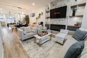 Un salon moderne avec une cheminée, un téléviseur fixé au mur et un coin repas.