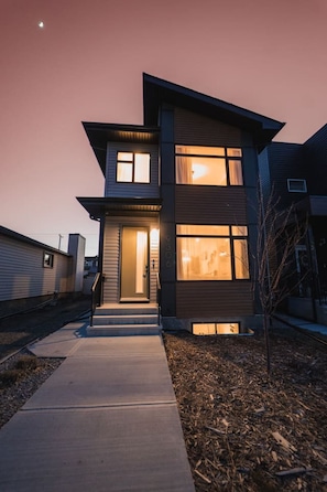 A modern two-story house with a visible front door, a small porch, and a driveway leading to the entrance. - Chic Central 3BR: Martini Bar & Patio. Near DT/WEM (Edmonton)
