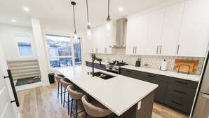 Une cuisine moderne dotée d’un grand îlot central, de tabourets de bar, d’une cuisinière et d’un réfrigérateur.