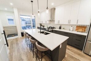 Une cuisine moderne dotée d’un grand îlot central, de tabourets de bar, d’une cuisinière et d’un réfrigérateur.