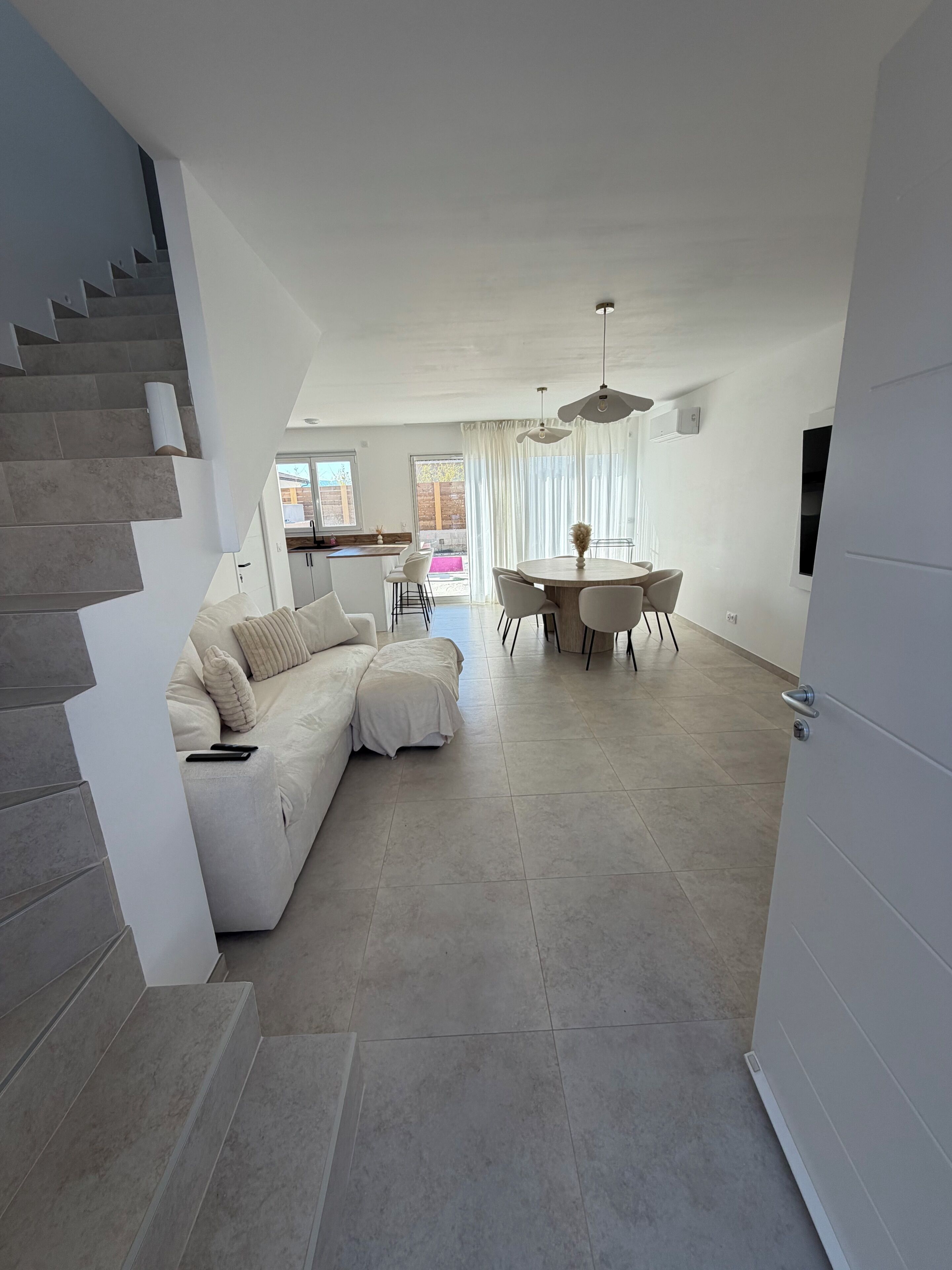 A modern living room with a sofa, dining table, and staircase.. Charming house 20 minutes from the beach