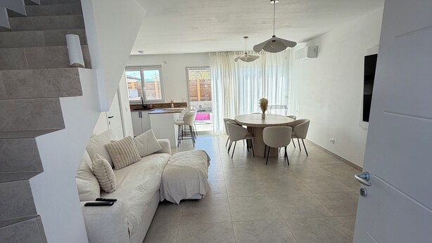 Een moderne woonkamer met een bank, eettafel en trap.