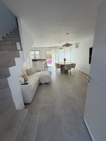 A modern living room with a sofa, dining table, and staircase.. Charming house 20 minutes from the beach