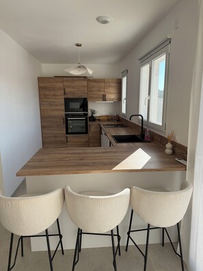 A modern kitchen with wooden cabinets, a central island, and a window.
