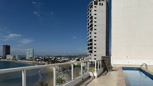 Ein Pool auf dem Dach mit freiem Blick auf Strand und Stadtlandschaft.