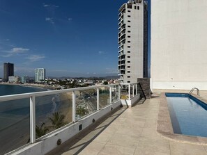 Ein Pool auf dem Dach mit freiem Blick auf Strand und Stadtlandschaft.
