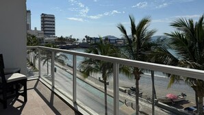 Ein Balkon mit Blick auf einen Strand, Palmen und einen wolkenlosen Himmel.