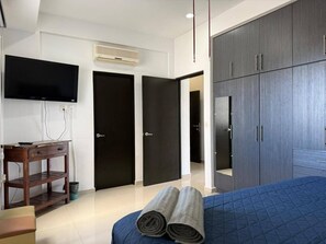 Ein Hotelzimmer mit Bett, Schreibtisch, Fernseher und Kleiderschrank.