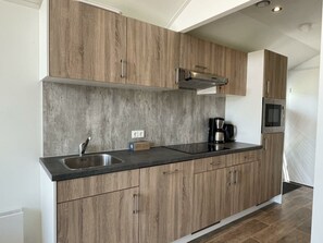 Een moderne keuken met houten kastjes, een roestvrijstalen spoelbak en een inbouwmagnetron.