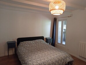 A bedroom with a bed, bedside tables, a hanging light fixture, a window with curtains, and a radiator. - Renovated 130 m² house in Saint-Quirin with a terrace, pergola, and Wi-Fi; sleeps up to 8 people (Saint-Quirin)