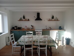 A kitchen with a dining table, chairs, a stove, and a sink. - Renovated 130 m² house in Saint-Quirin with a terrace, pergola, and Wi-Fi; sleeps up to 8 people (Saint-Quirin)
