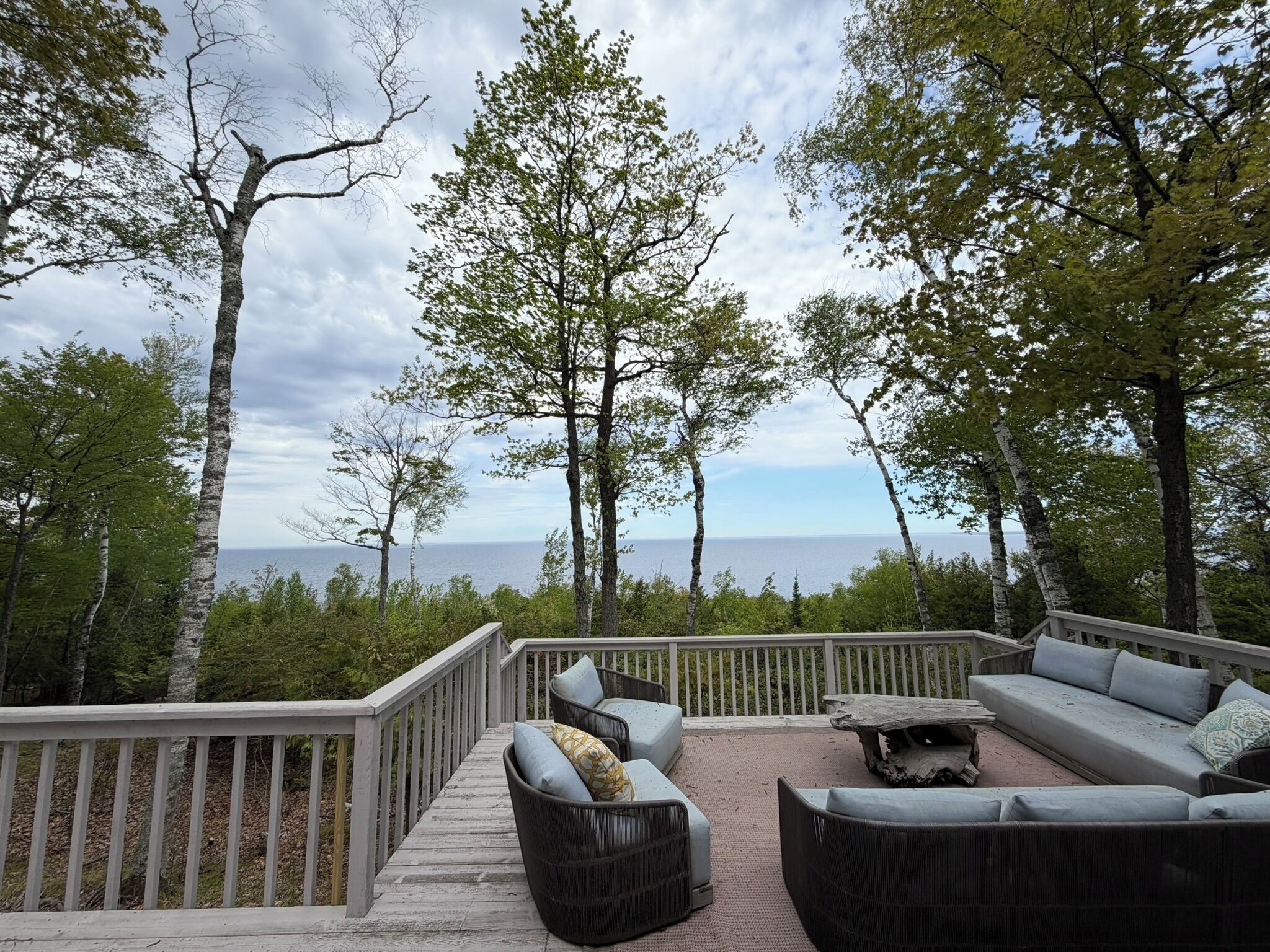 Eine Terrasse mit Gartenmöbeln, einem Geländer und Blick aufs Meer.