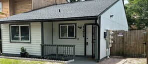 A small, single-story house with a front porch, a mailbox, and a wooden fence.