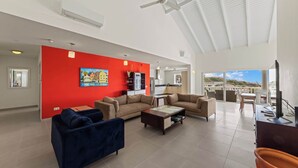 A spacious living area with a red accent wall, two sofas, a coffee table, and a balcony with a view.