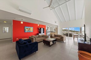 Ein geräumiger Wohnbereich mit roter Akzentwand, zwei Sofas, einem Couchtisch und einem Balkon mit Blick.