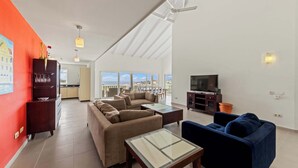 A spacious living area with a large sofa set, a coffee table, and a TV.