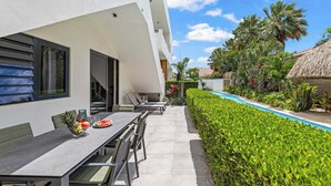 Ein moderner Essbereich im Freien mit Pool und gepflegter Bepflanzung.