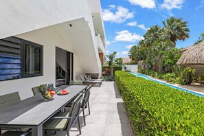 Ein moderner Essbereich im Freien mit Pool und gepflegter Bepflanzung.