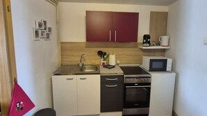 Una cocina compacta con lavamanos, microondas, estufa y armarios.