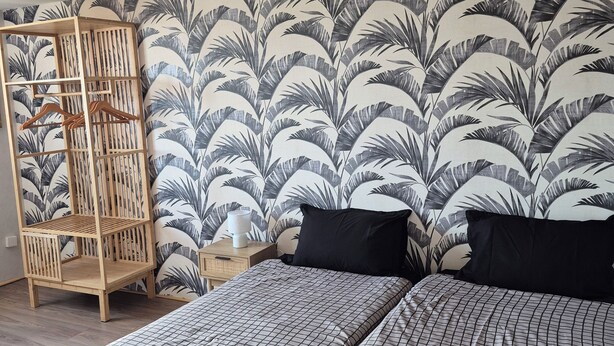 Un dormitorio con dos camas, un armario de madera y una pared con un diseño de hojas.