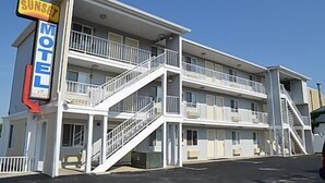 Un motel con una estructura de dos pisos, una escalera que conduce al piso superior y un cartel que indica que es un motel.