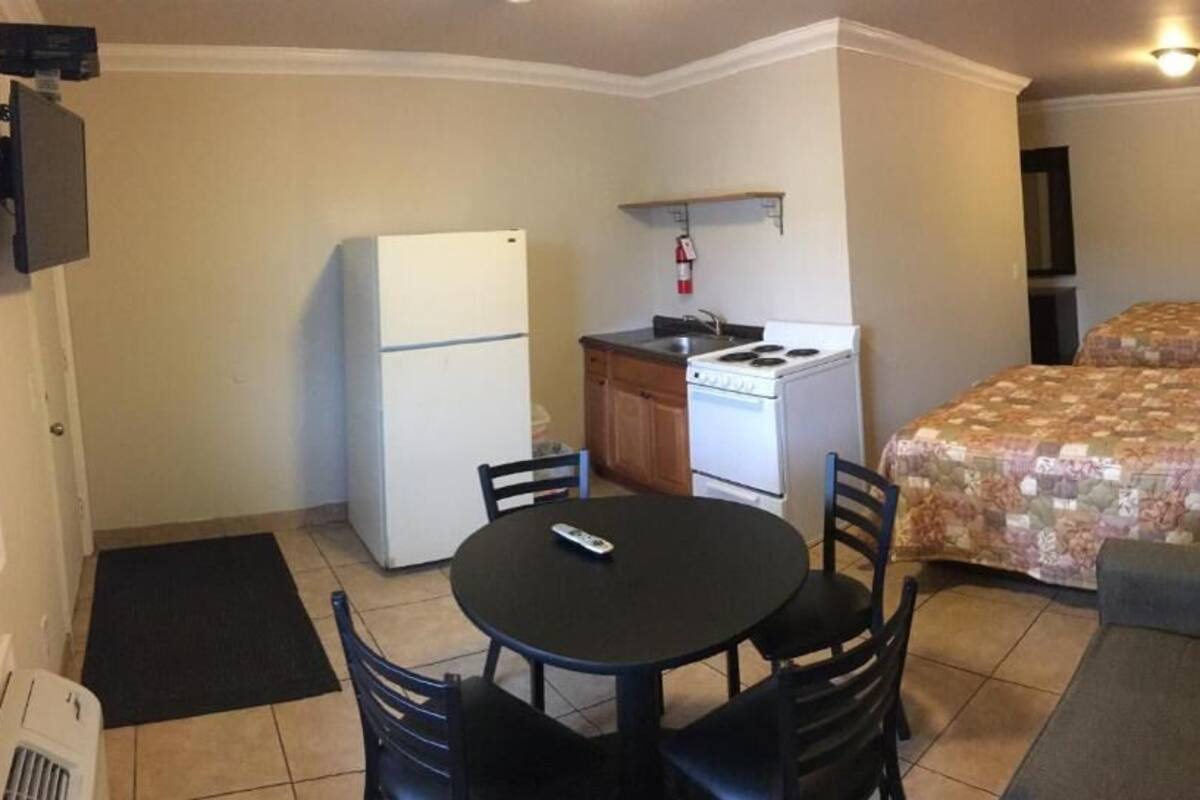 Una habitación compacta con kitchenette, una mesa de comedor con sillas, un sofá y dos camas.