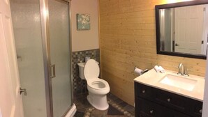 Un baño con inodoro, lavabo, espejo y zona de ducha.