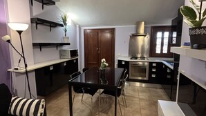 A modern kitchen with a dining area, a sofa, and a lamp. - Calixa - Sheaves - Comfortable apartment for two people, private parking. (Cagliari)
