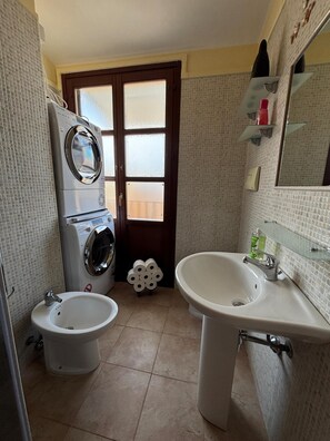 Ein kleines Badezimmer mit Toilette, Bidet, Waschbecken und einer Waschmaschine.
