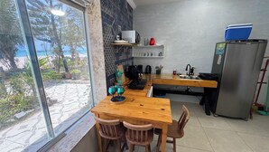 Eine Küche mit einem Holztisch, Stühlen, einem Kühlschrank und Blick ins Freie.