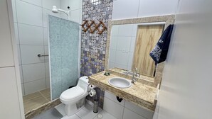 Ein Badezimmer mit Dusche, Toilette, Waschbecken und Spiegel.